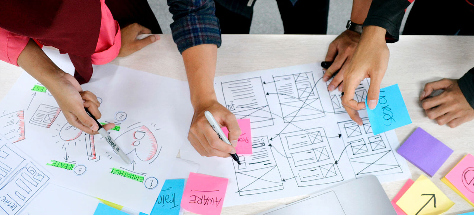 Designers looking over ux sketches scattered across a table