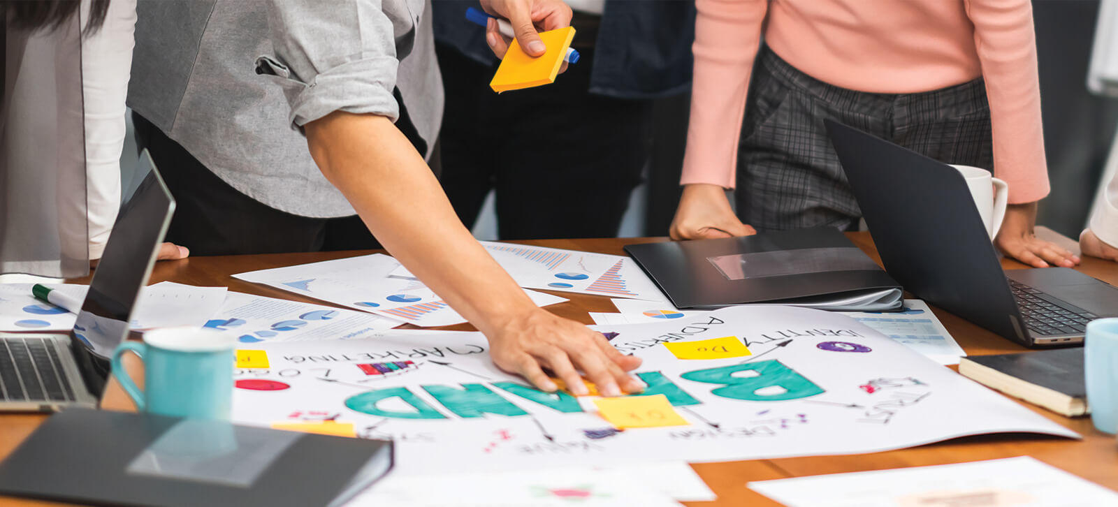 A group of people brainstorming while hovering over a table