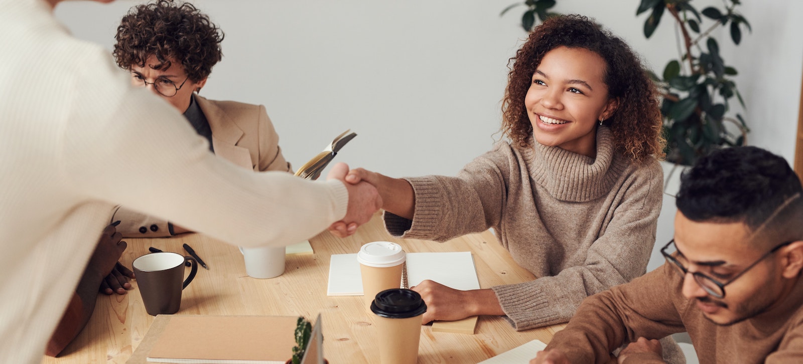 coworkers of different races and sex shaking hands in a meeting room