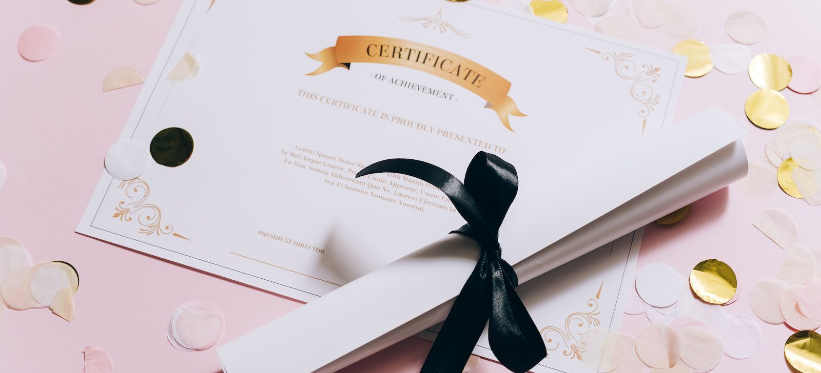 Rolled White Paper and a Certificate on a Pink Surface