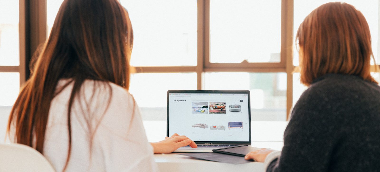 two women talking while looking at laptop computer