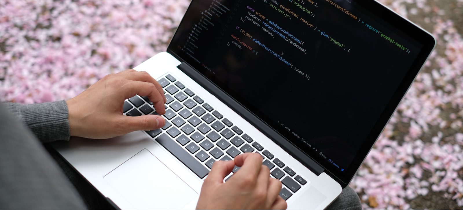 person using macbook pro on pink and white floral textile