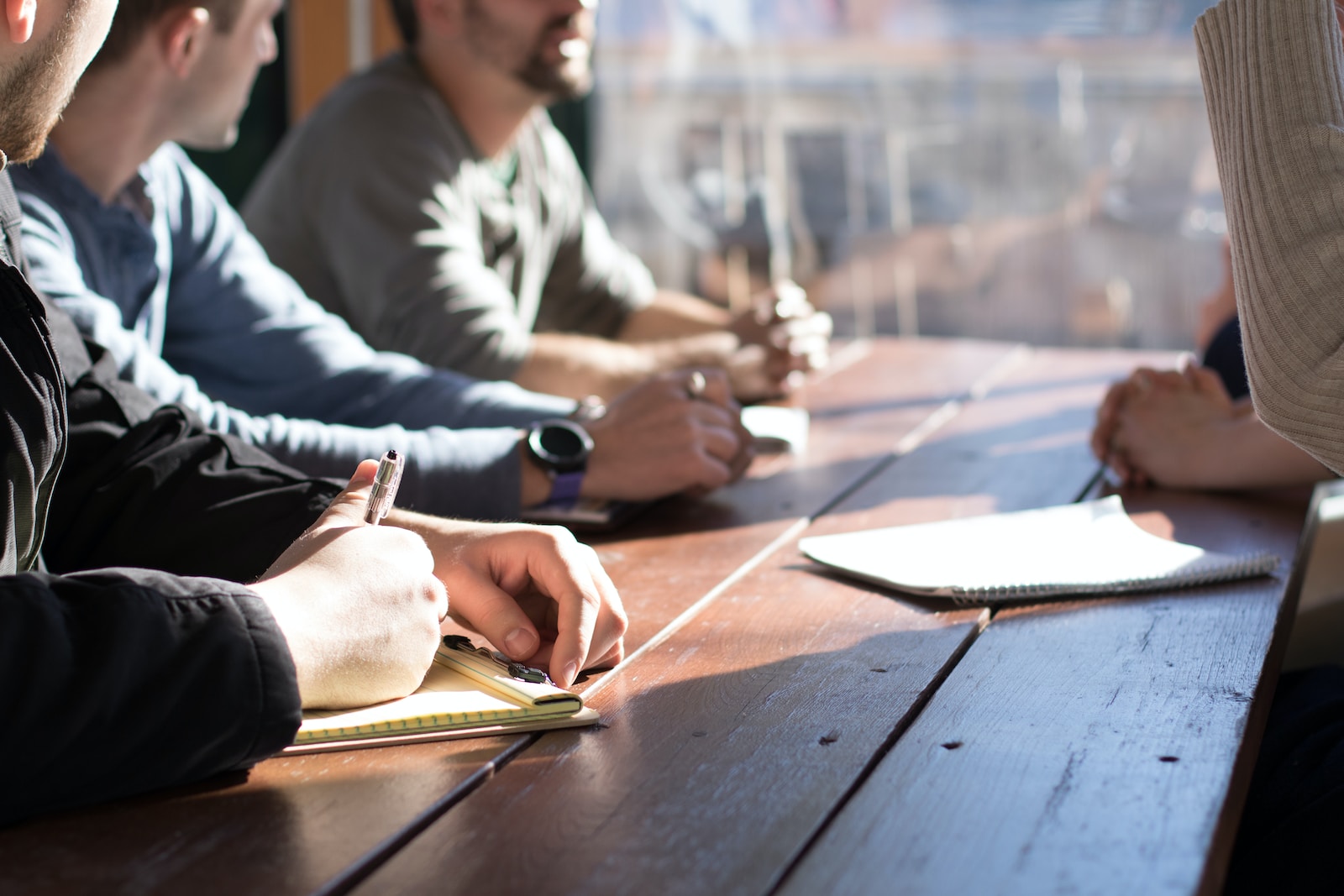 people sitting and talking at table with notepads