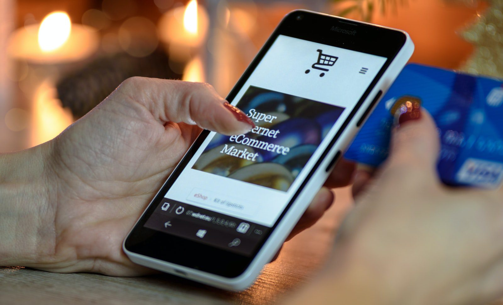 Someone using a smartphone to make a purchase online with a blue credit card