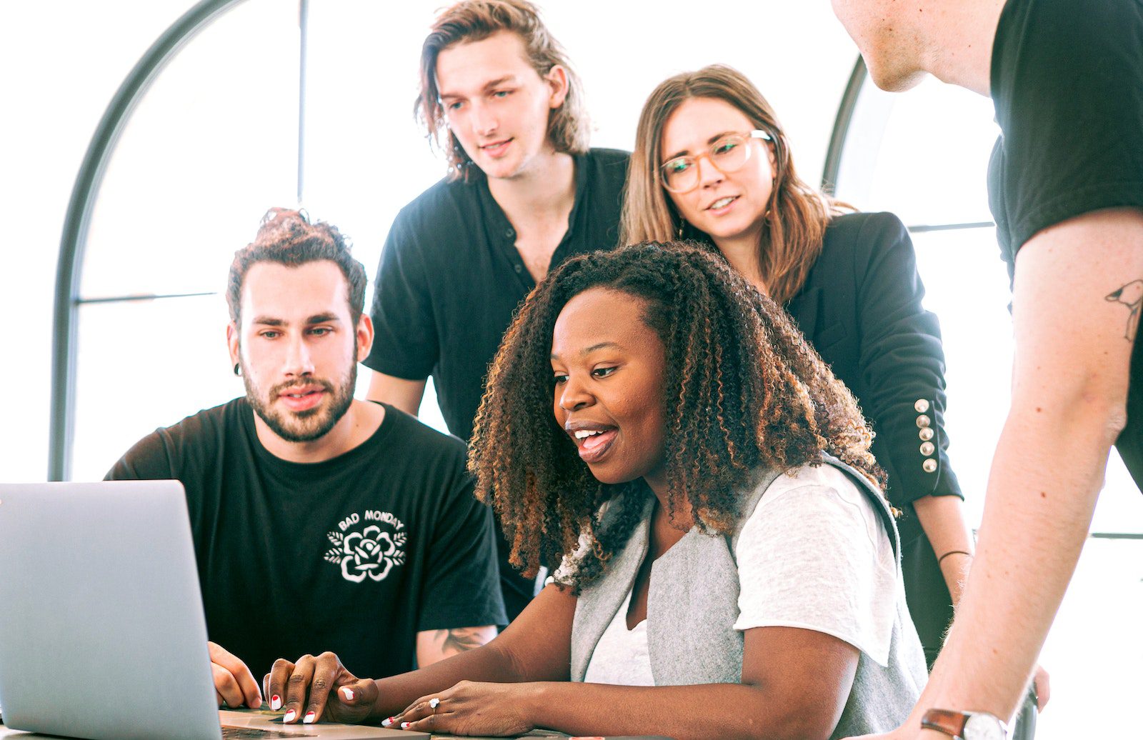 People gathered around a computer laughing and smiling