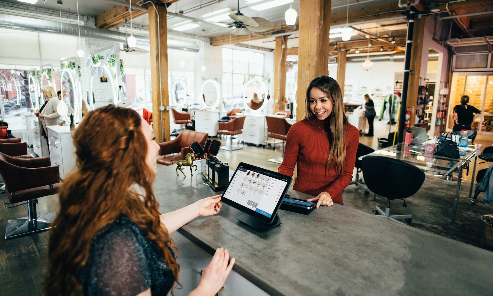 A customer making a credit card purchase from a cashier at a boutique store counter