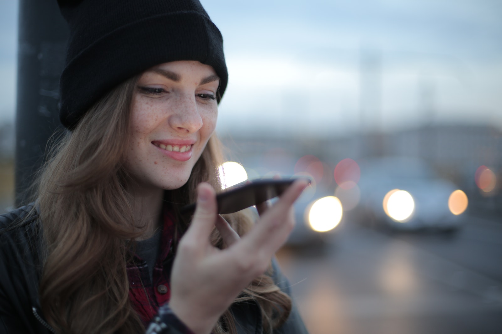 woman holding and speaking into smartphone