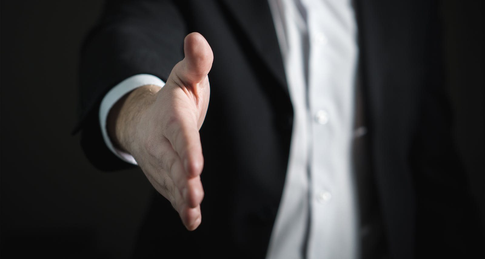 Close-up of man in a suit reaching out for a handshake