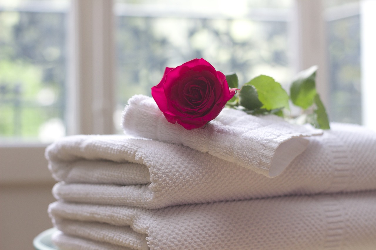 white towels folded with red rose on top